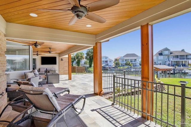 view of patio / terrace with a water view, an outdoor hangout area, a ceiling fan, fence, and a residential view