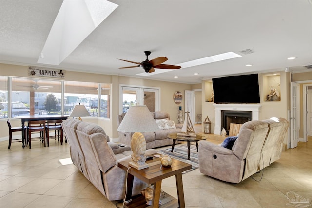 living area featuring a skylight, a fireplace, and crown molding