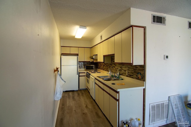 kitchen featuring white appliances, dark wood-type flooring, sink, a textured ceiling, and tasteful backsplash