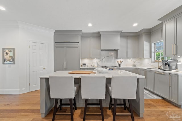 kitchen with light hardwood / wood-style floors, premium range hood, and a kitchen island