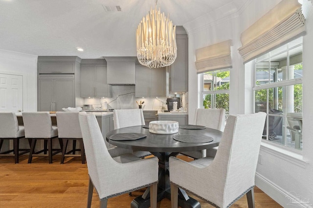 dining area featuring light hardwood / wood-style floors, crown molding, and a chandelier