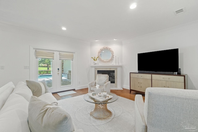 living room with french doors, crown molding, and light wood-type flooring