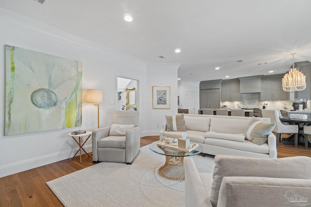 living room featuring crown molding, hardwood / wood-style flooring, and a notable chandelier