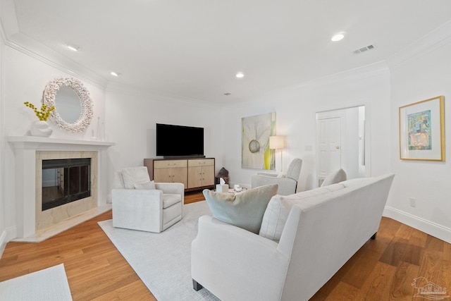 living room featuring light hardwood / wood-style floors, a high end fireplace, and ornamental molding