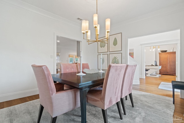 dining area featuring crown molding, light hardwood / wood-style flooring, and a notable chandelier