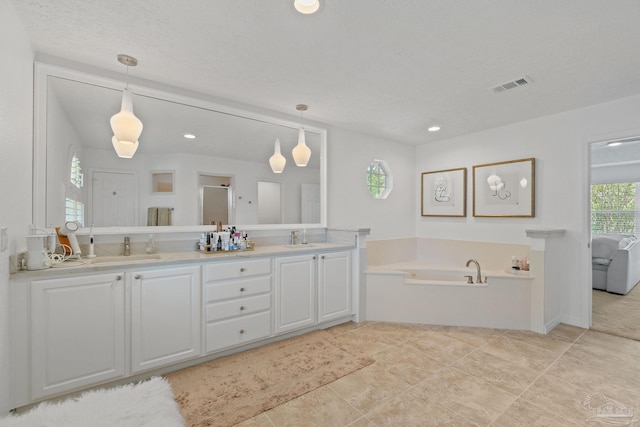 bathroom with vanity, a bathtub, a textured ceiling, and tile patterned flooring