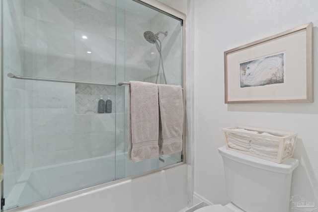 bathroom featuring toilet and shower / bath combination with glass door