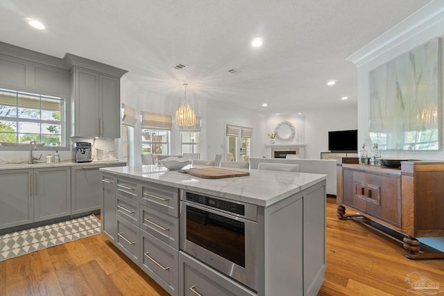 kitchen with light hardwood / wood-style flooring, a wealth of natural light, a kitchen island, and gray cabinets