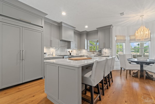 kitchen featuring light hardwood / wood-style floors, decorative light fixtures, a center island, and gray cabinetry