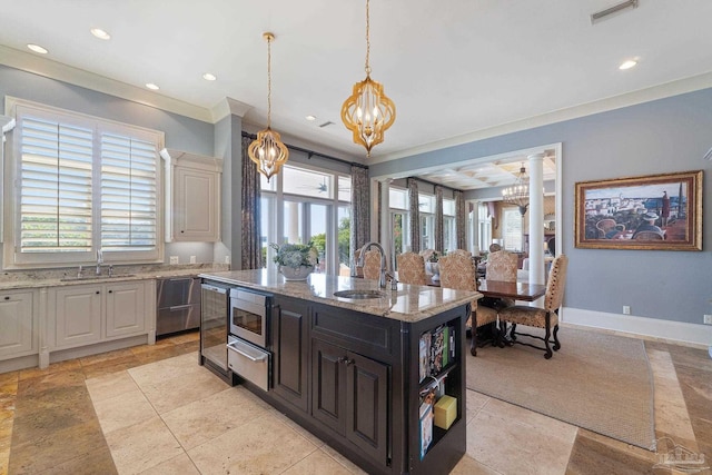 kitchen with a kitchen island with sink, a wealth of natural light, an inviting chandelier, and sink