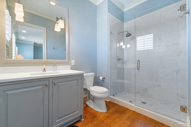 bathroom with toilet, hardwood / wood-style floors, ornamental molding, vanity, and a shower with shower door