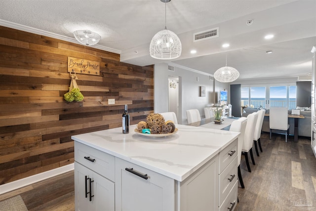 kitchen featuring white cabinetry, light stone counters, pendant lighting, and a center island