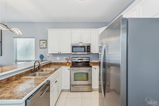 kitchen with pendant lighting, appliances with stainless steel finishes, sink, and white cabinetry