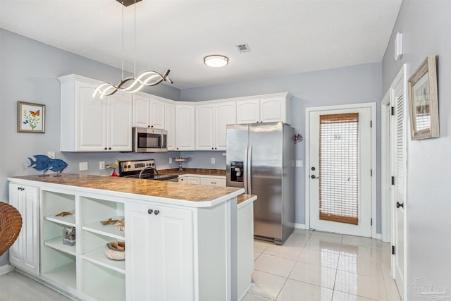 kitchen featuring white cabinets, kitchen peninsula, hanging light fixtures, appliances with stainless steel finishes, and light tile patterned floors