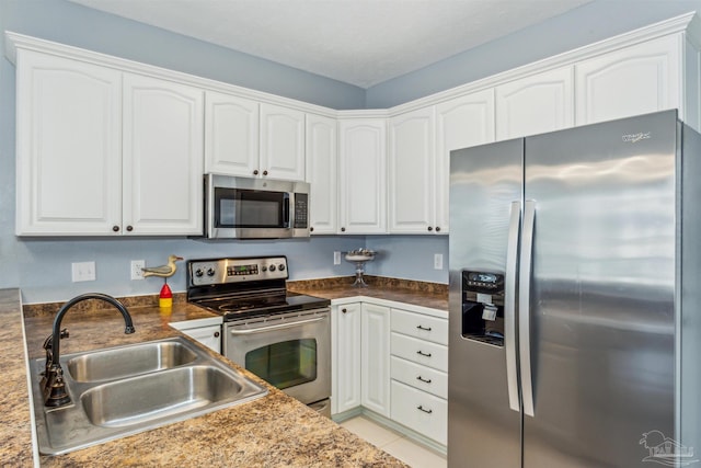 kitchen with white cabinets, appliances with stainless steel finishes, sink, and light tile patterned floors