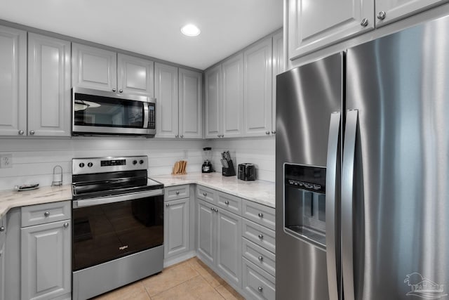 kitchen featuring gray cabinets, light stone counters, and appliances with stainless steel finishes