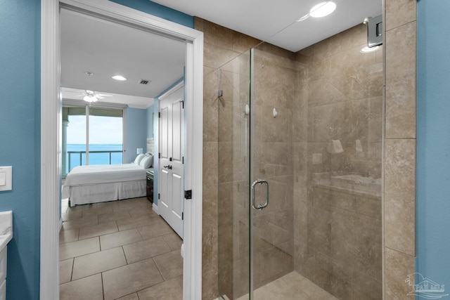 bathroom with a water view, a shower with door, and ceiling fan