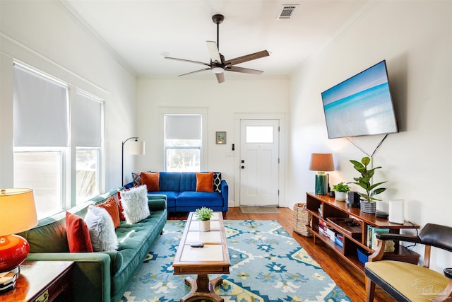 living room featuring hardwood / wood-style floors, ceiling fan, and crown molding