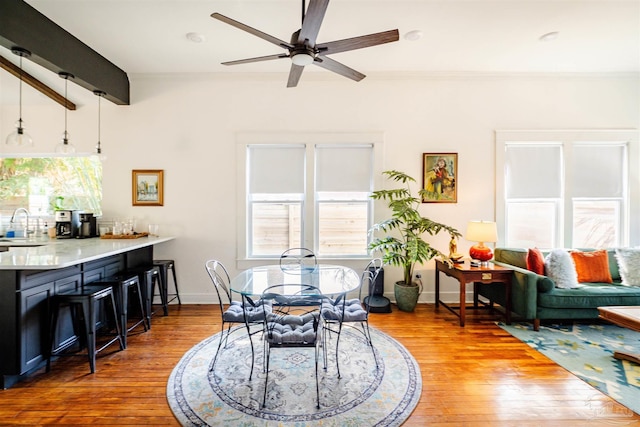 dining area with beamed ceiling, hardwood / wood-style flooring, ceiling fan, and sink