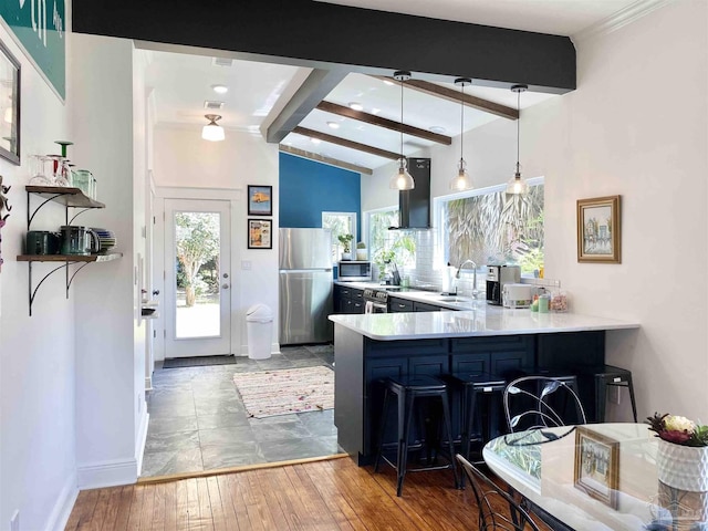 kitchen with stainless steel appliances, kitchen peninsula, pendant lighting, a breakfast bar, and hardwood / wood-style flooring