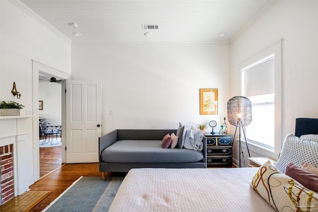 bedroom with crown molding, a fireplace, and dark hardwood / wood-style floors