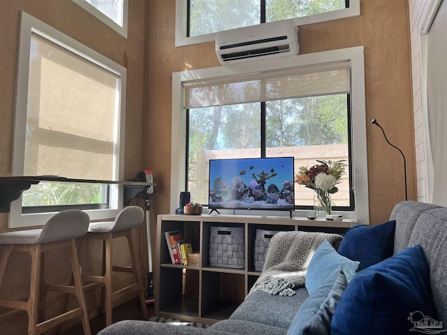 living room featuring a wall mounted AC, wooden walls, and a healthy amount of sunlight