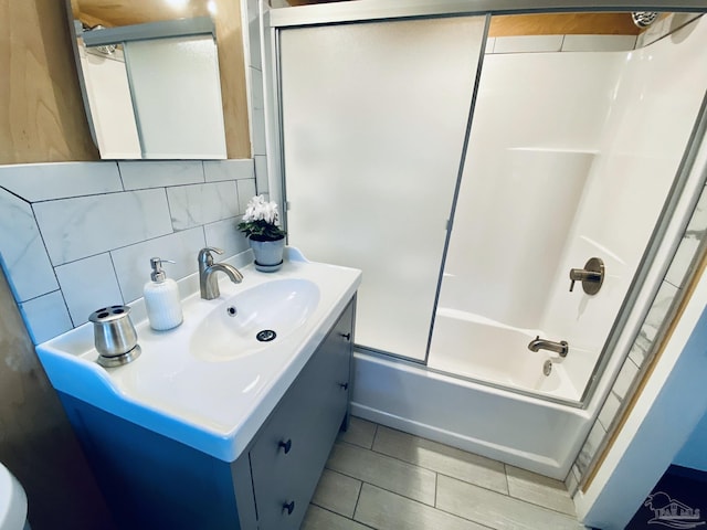 bathroom featuring shower / bath combination with glass door, vanity, backsplash, and tile patterned floors