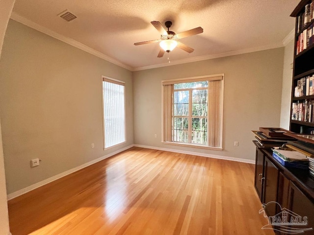 empty room with a textured ceiling, crown molding, ceiling fan, and light hardwood / wood-style floors