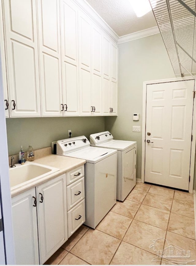 laundry area featuring light tile patterned floors, cabinets, washing machine and clothes dryer, and sink