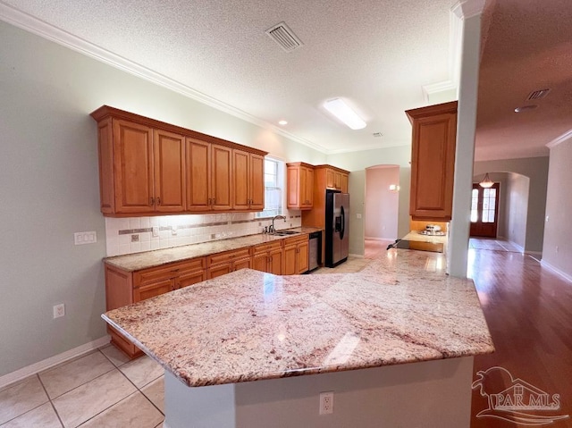 kitchen featuring a healthy amount of sunlight, kitchen peninsula, appliances with stainless steel finishes, and light hardwood / wood-style floors