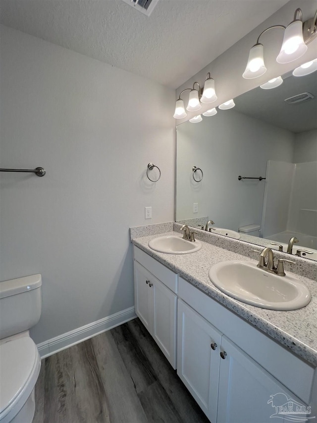 bathroom with vanity, hardwood / wood-style floors, toilet, and a textured ceiling