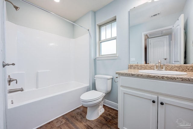 full bathroom with vanity, hardwood / wood-style floors, washtub / shower combination, and toilet