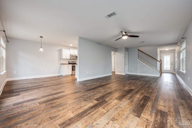 unfurnished living room featuring stairway, a ceiling fan, baseboards, visible vents, and dark wood-style flooring