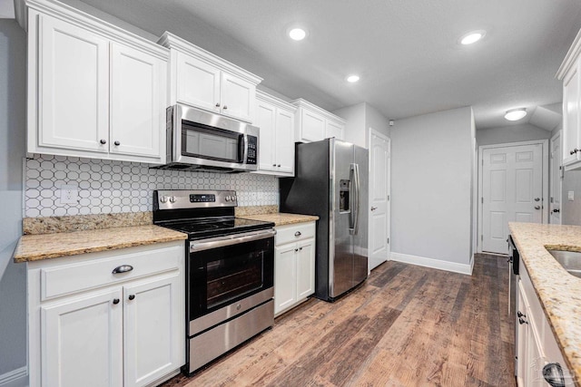 kitchen with light stone counters, white cabinetry, dark wood-type flooring, and appliances with stainless steel finishes