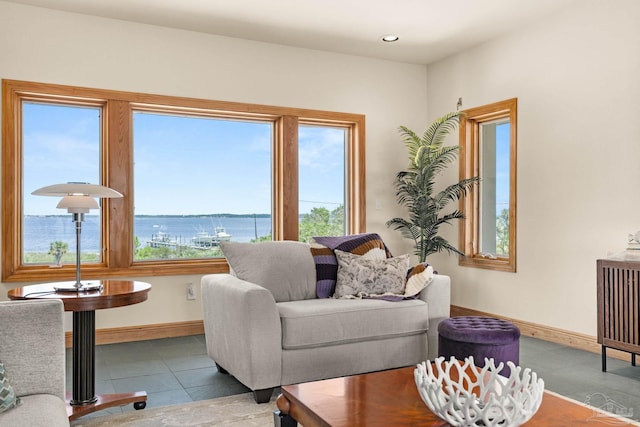 tiled living room featuring recessed lighting, baseboards, and a water view