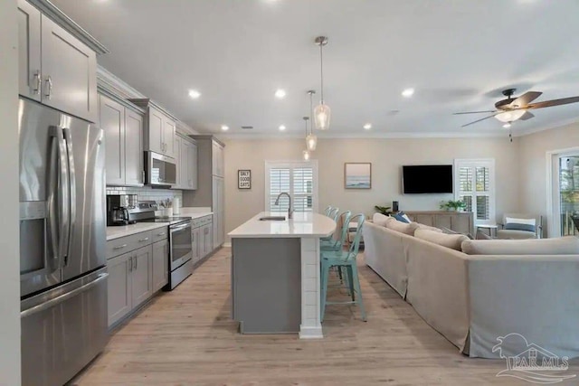 kitchen with appliances with stainless steel finishes, hanging light fixtures, tasteful backsplash, and gray cabinetry