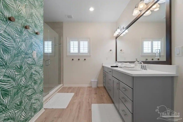 bathroom with wood-type flooring, a shower with shower door, and vanity