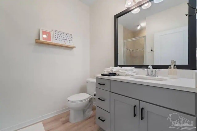 bathroom with hardwood / wood-style floors, vanity, toilet, and an enclosed shower