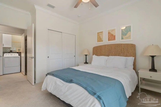 carpeted bedroom featuring a closet, washer / dryer, ceiling fan, and crown molding