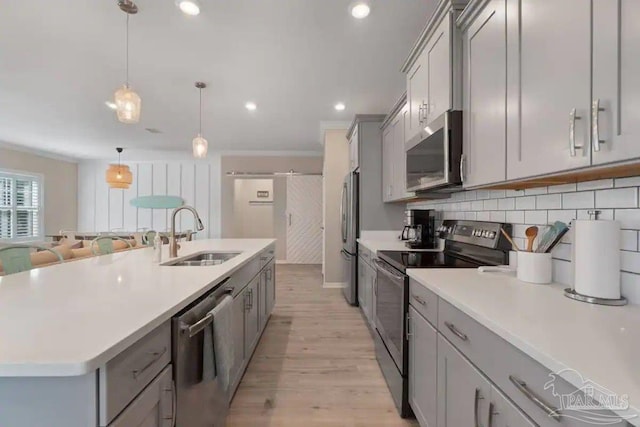 kitchen featuring pendant lighting, sink, gray cabinetry, appliances with stainless steel finishes, and light hardwood / wood-style floors