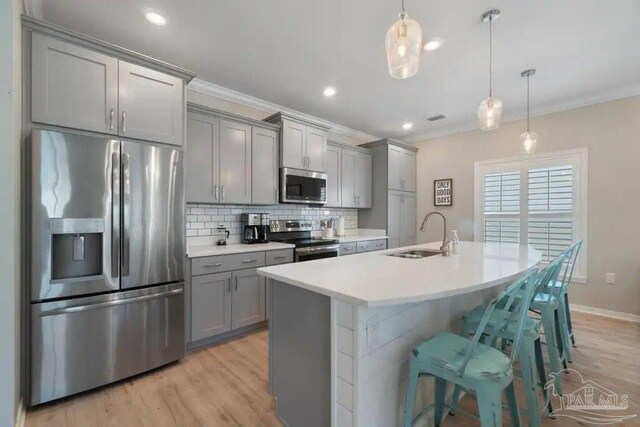 6635 Carlinga Dr, Pensacola, FL 32507 - kitchen with appliances with stainless steel finishes, a sink, gray cabinets, decorative backsplash, and a center island with sink