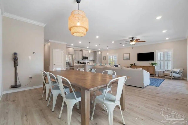 dining space with light wood-type flooring, a healthy amount of sunlight, and ornamental molding