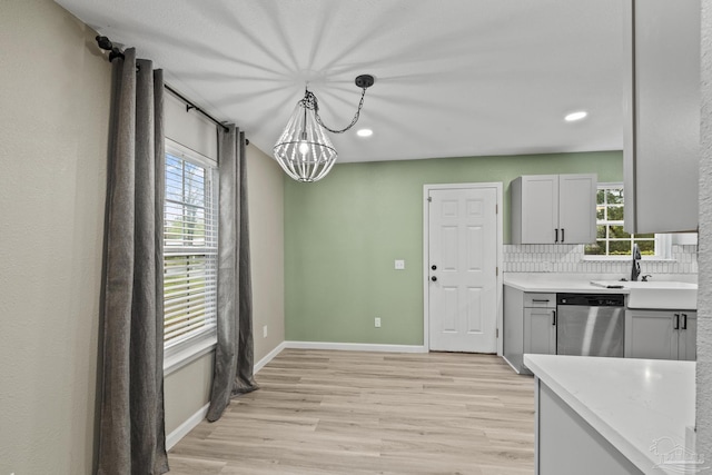 3985 Whitehall Dr, Pace, FL 32571 - kitchen featuring an inviting chandelier, decorative backsplash, stainless steel dishwasher, a sink, and light wood finished floors