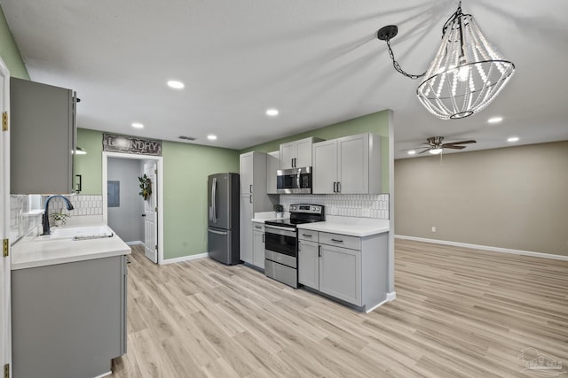 3985 Whitehall Dr, Pace, FL 32571 - kitchen with a sink, gray cabinetry, stainless steel appliances, ceiling fan with notable chandelier, and light wood-style floors