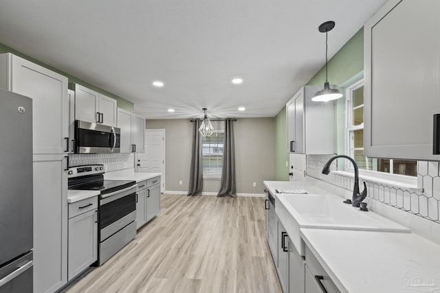 3985 Whitehall Dr, Pace, FL 32571 - kitchen with light countertops, light wood-style flooring, appliances with stainless steel finishes, a sink, and hanging light fixtures