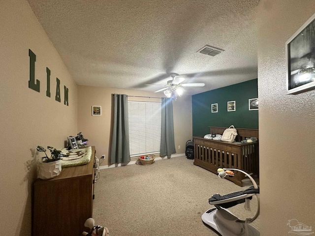 carpeted bedroom with ceiling fan and a textured ceiling