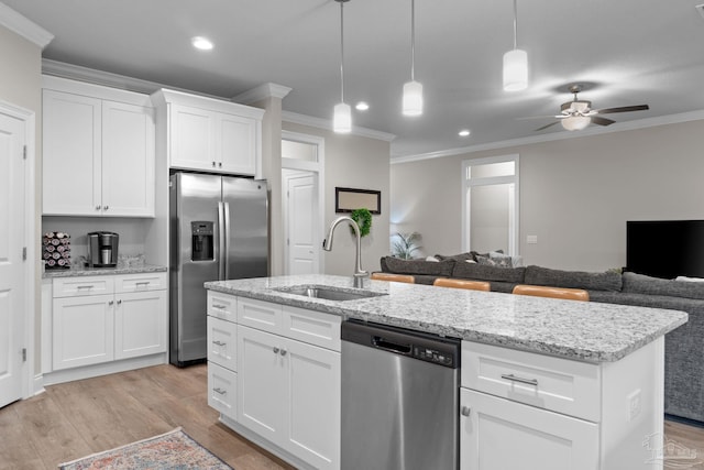 kitchen featuring stainless steel appliances, a sink, crown molding, open floor plan, and ceiling fan