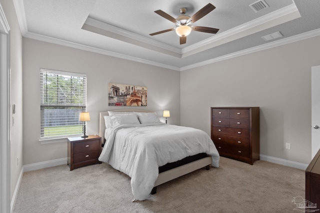 bedroom featuring a tray ceiling, crown molding, light carpet, and baseboards