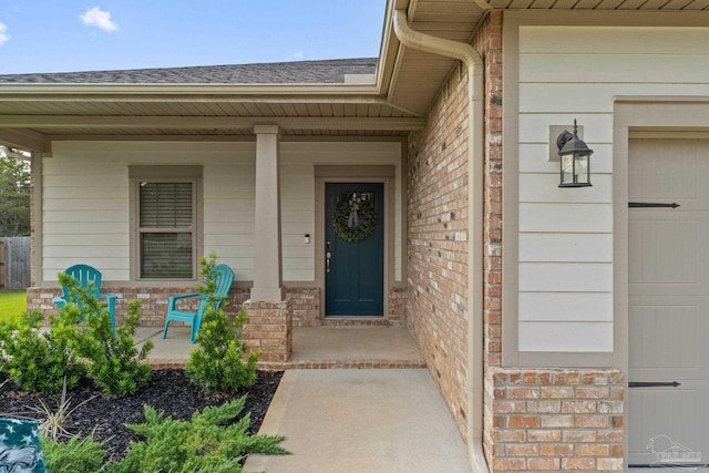 property entrance featuring a porch, brick siding, and roof with shingles