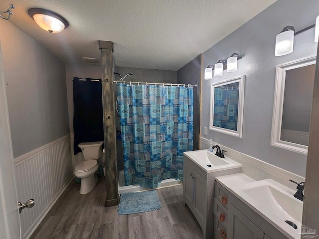 bathroom with a textured ceiling, vanity, a shower with shower curtain, hardwood / wood-style floors, and toilet